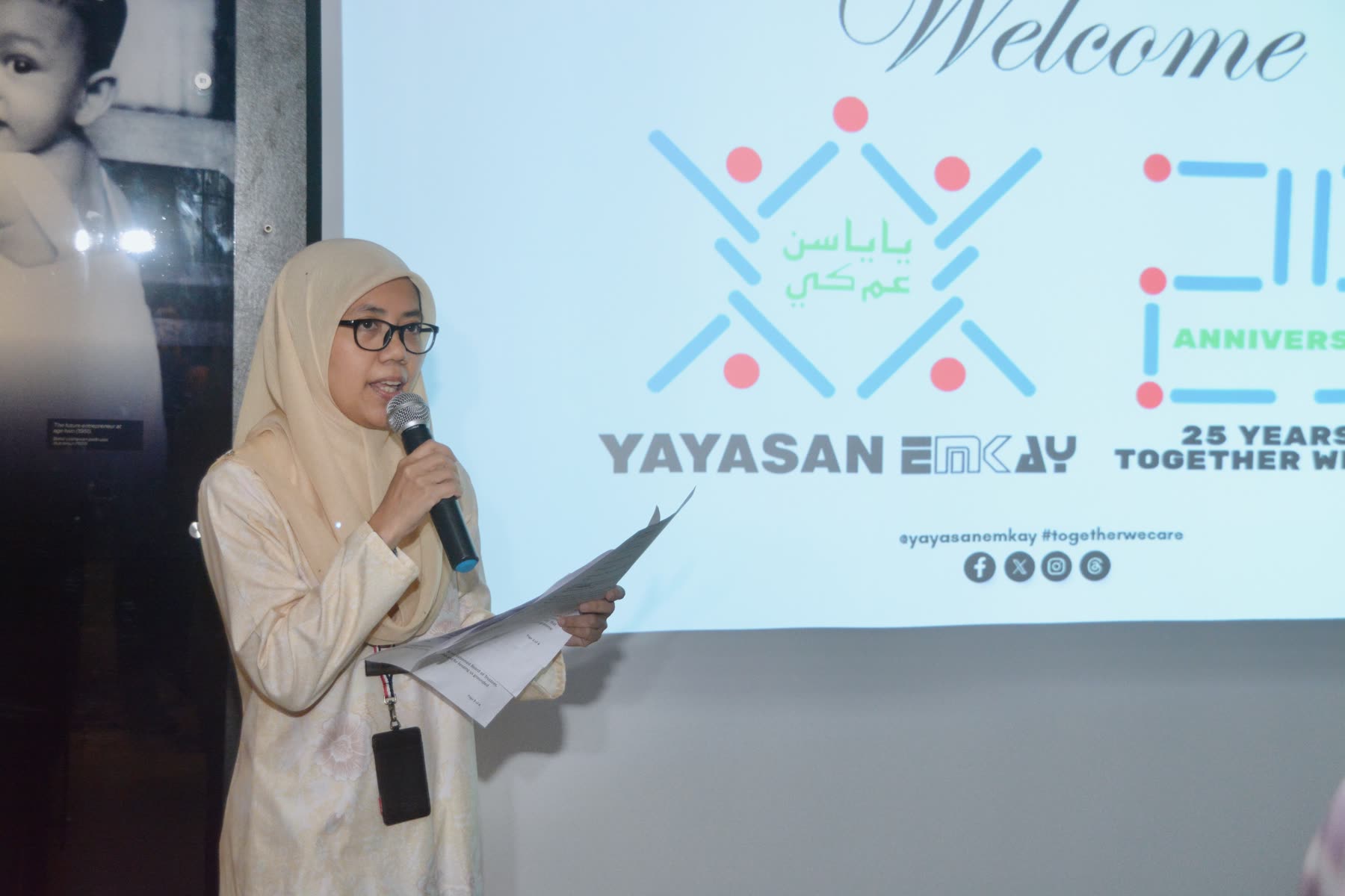 A speaker welcoming guests to the Yayasan EMKAY anniversary event